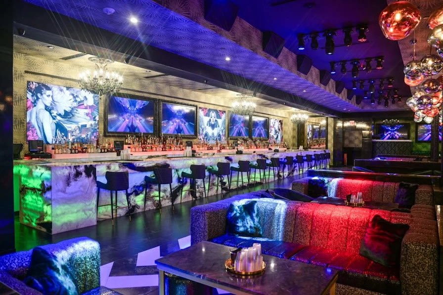 A curved red and blue lit banquette faces SOHO's illuminated marble bar, framed artwork and chandeliers.